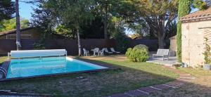a swimming pool with a bench in a yard at Les Hôtes du Paradis in Forges