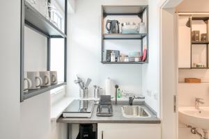 una pequeña cocina con lavabo y espejo en BLEIBEREI Apartments en Göttingen