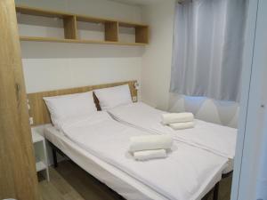 a bed with white sheets and two towels on it at Camping Village Il Poggetto in Troghi