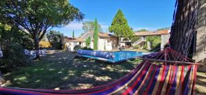 a hammock in a yard with a swimming pool at Les Hôtes du Paradis in Forges