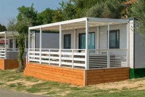 Casa móvil con porche y barandilla blanca en Camping Fontanelle, en Moniga del Garda