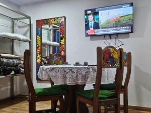 a table with two chairs and a tv on a wall at Solar dos Reis - Apartamento Turmalina in Ouro Preto