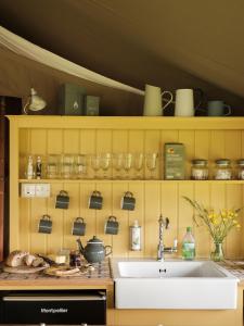 a kitchen with a sink and glasses on a shelf at Black Pig Retreats Luxury Glamping in Shaftesbury