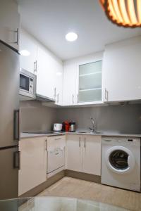 cocina con armarios blancos y lavadora en Apartamento Premium Playa Altar 2, en Barreiros