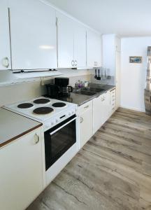 a white kitchen with a stove and a sink at Holiday home - Semesterhus Solnedgång in Blattniksele