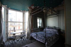 a bedroom with a canopy bed and a table and a window at Chimera House in Brighton & Hove