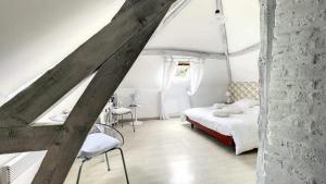 a white bedroom with a bed and chairs in it at Le Clos in Hucqueliers