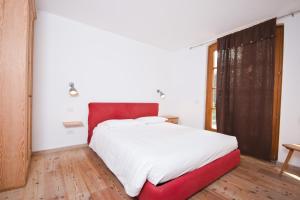 - une chambre avec un grand lit et une tête de lit rouge dans l'établissement Hotel Martinelli, à Ronzo Chienis
