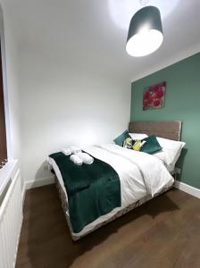 - une chambre avec un lit et une couette verte et blanche dans l'établissement Md Stays, à Londres