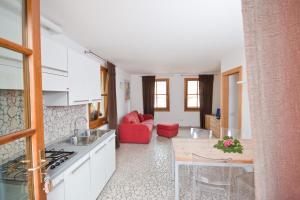 a kitchen with white cabinets and a red couch at Hotel Martinelli in Ronzo Chienis