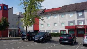eine Gruppe von Autos, die auf einem Parkplatz geparkt sind in der Unterkunft Ibis Budget Montbéliard in Montbéliard
