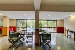 a dining room with a table and chairs and windows at Amazinn Villa in Lonavala