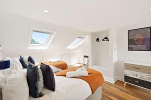 a white bedroom with a bed and a television at 2 Bed Duplex Apartment in Wimbledon in London