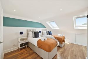 two beds in a white room with two windows at 2 Bed Duplex Apartment in Wimbledon in London