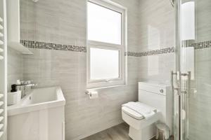 a white bathroom with a toilet and a sink at 2 Bed Duplex Apartment in Wimbledon in London