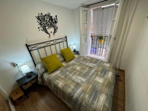 a bedroom with a bed with yellow pillows and a window at La Fantàstica de la Part Alta in Tarragona