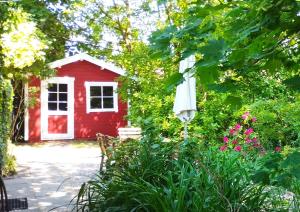 een rood huis met een witte deur en een tuin bij Upleward Cottage in Krummhörn