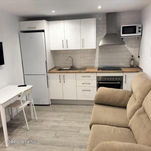 una cocina con armarios blancos y un sofá en una habitación en SANTA CLARA Con opción a Parking, en Jaén
