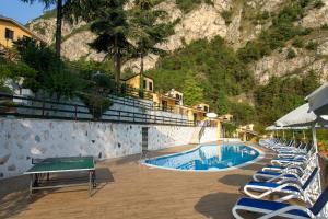 un resort con piscina, sedie e montagna di Residence Oasi a Limone sul Garda