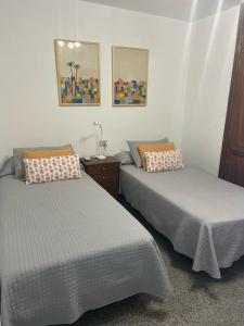 a bedroom with two beds and a table and pictures at Playa Chica apartment in Puerto del Carmen