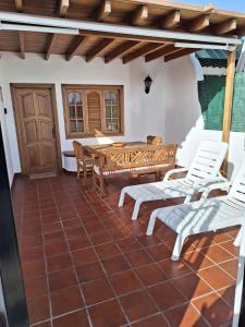 un patio con sillas blancas y una mesa de madera. en Playa Chica apartment, en Puerto del Carmen