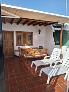 patio z białymi krzesłami i drewnianym stołem w obiekcie Playa Chica apartment w Puerto del Carmen