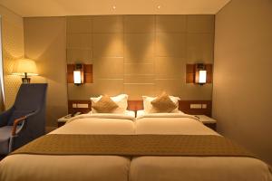 MandyaHotel Amaravathi的一间带床和椅子的酒店房间