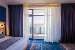 a hotel room with a bed and a large window at Gino Seaside Tbilisi, Trademark Collection by Wyndham in Tbilisi City