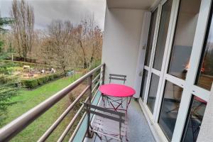 un taburete rojo sentado en el balcón de un edificio en Le Nid de l'Yvette en Chilly-Mazarin