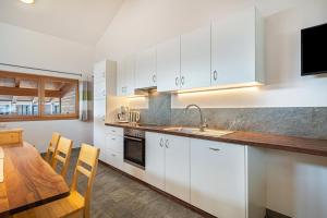 a kitchen with white cabinets and a table and a television at Seppnerhof Ferienwohnung Edelweiss in Pfelders +12 photos