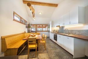 cocina con armarios blancos y mesa de madera en Seppnerhof Ferienwohnung Edelweiss, en Pfelders