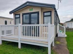 a tiny house with a porch and a white fence at 208 Holiday Resort Unity 3 bed Passes included in Brean