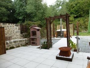 um jardim com um arco de madeira e um grelhador em Maison Galloise em Auzances