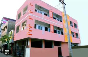 a pink building with many windows on a street at ‌‌Florence guest house in Puducherry