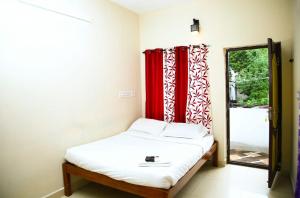 a bedroom with a bed with red curtains and a mirror at ‌‌Florence guest house in Pondicherry