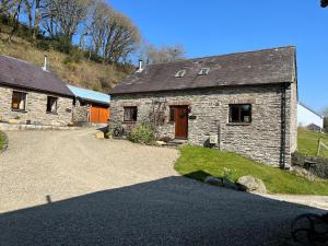 a stone house with a driveway in front of it at Troedyrhiw Holiday Cottages in Cardigan