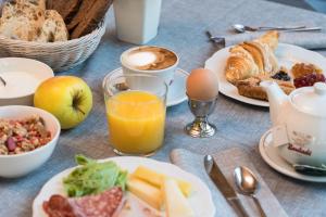 a table topped with plates of breakfast food and orange juice at Hotel Martinelli in Ronzo Chienis