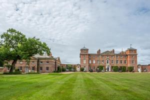 um grande edifício de tijolos com um grande campo de relva em The East Wing BB em Wymondham