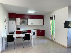 kuchnia z czerwonymi szafkami oraz białym stołem i krzesłami w obiekcie Apartamento Pueblo Cid w mieście El Verger