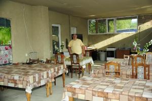 a man standing in a room with tables and chairs at Guesthouse in Sadgeri in Borjomi