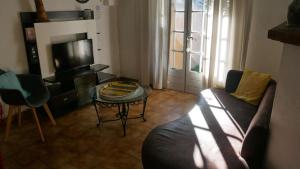 ein Wohnzimmer mit einem Sofa, einem Tisch und einem TV in der Unterkunft Mas Maurane - Le Bougainvillier aux portes d'ARLES in Tarascon