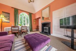 uma sala de estar com um sofá roxo e uma televisão em The Gate House BB em Wymondham