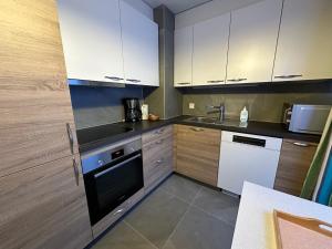 - une cuisine avec des appareils blancs et des armoires en bois dans l'établissement Les Dents du Midi A10, à Leysin