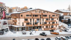 een appartementencomplex met auto's in de sneeuw bij Alpenstyle Resort Fieberbrunn by AlpenTravel in Fieberbrunn