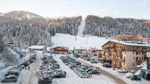 a parking lot full of cars in a snow covered town at Alpenstyle Resort Fieberbrunn by AlpenTravel in Fieberbrunn
