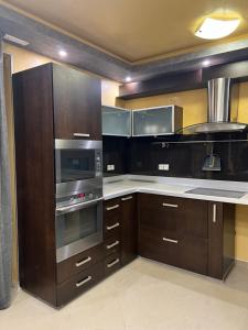 uma cozinha com armários de madeira e electrodomésticos de aço inoxidável em Апартамент БМ em Vratsa