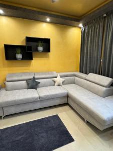 a living room with a large couch and a yellow wall at Апартамент БМ in Vratsa