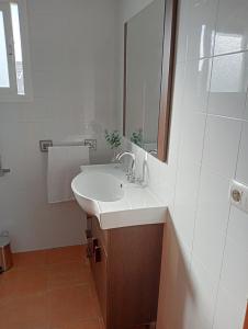 Baño blanco con lavabo y espejo en Vivienda turistica hinojos, en Hinojos