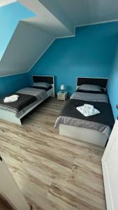 two beds in a bedroom with blue walls and wooden floors at Charlie&Blueberries 1 in Belgrade