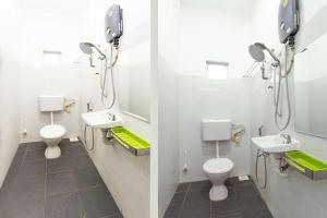 ein Badezimmer mit 2 WCs, 2 Waschbecken und Spiegeln in der Unterkunft Sg Rengit City Resort 1 in Kampung Sungai Rengit